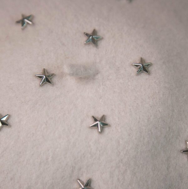 Krémový baret se stříbrnými hvězdičkami.